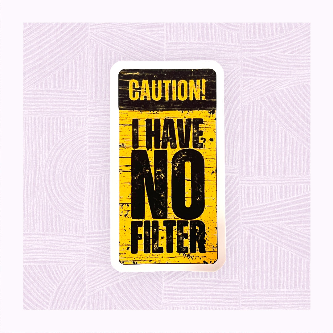 Die cut sticker with a yellow and black distressed background, with the phrase ‘Caution! I Have No Filter’.