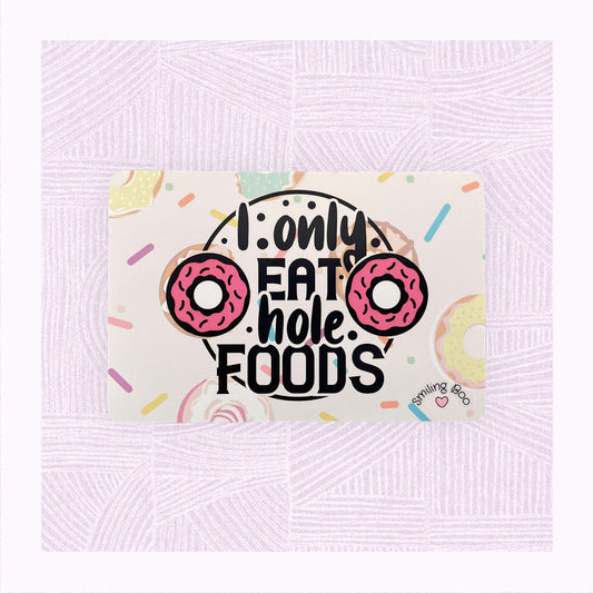 Postcard art print with printed background of raining doughnuts, and the phrase ‘I only eat hole foods’ with a pink doughnut either side.