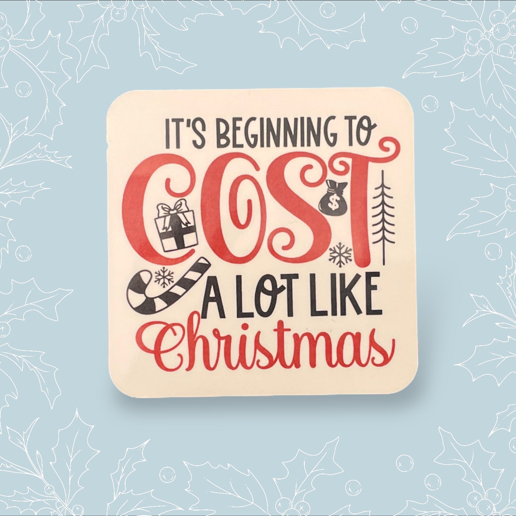 Square coaster with ‘It’s beginning to cost a lot like Christmas’ in black and red with festive embellishments