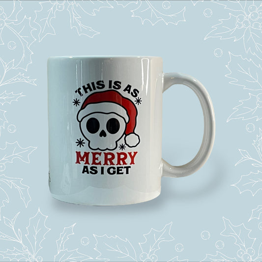 Ceramic mug with ‘This is as merry as I get’ on it with a skull wearing a Santa hat on