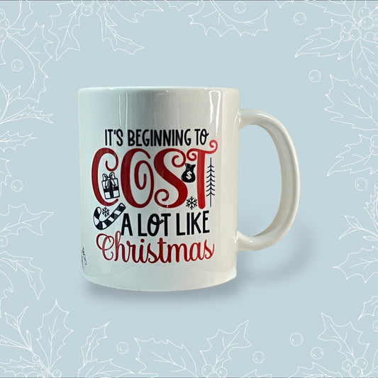 Ceramic mug with ‘It’s beginning to cost a lot like Christmas’ in black and red with festive embellishments